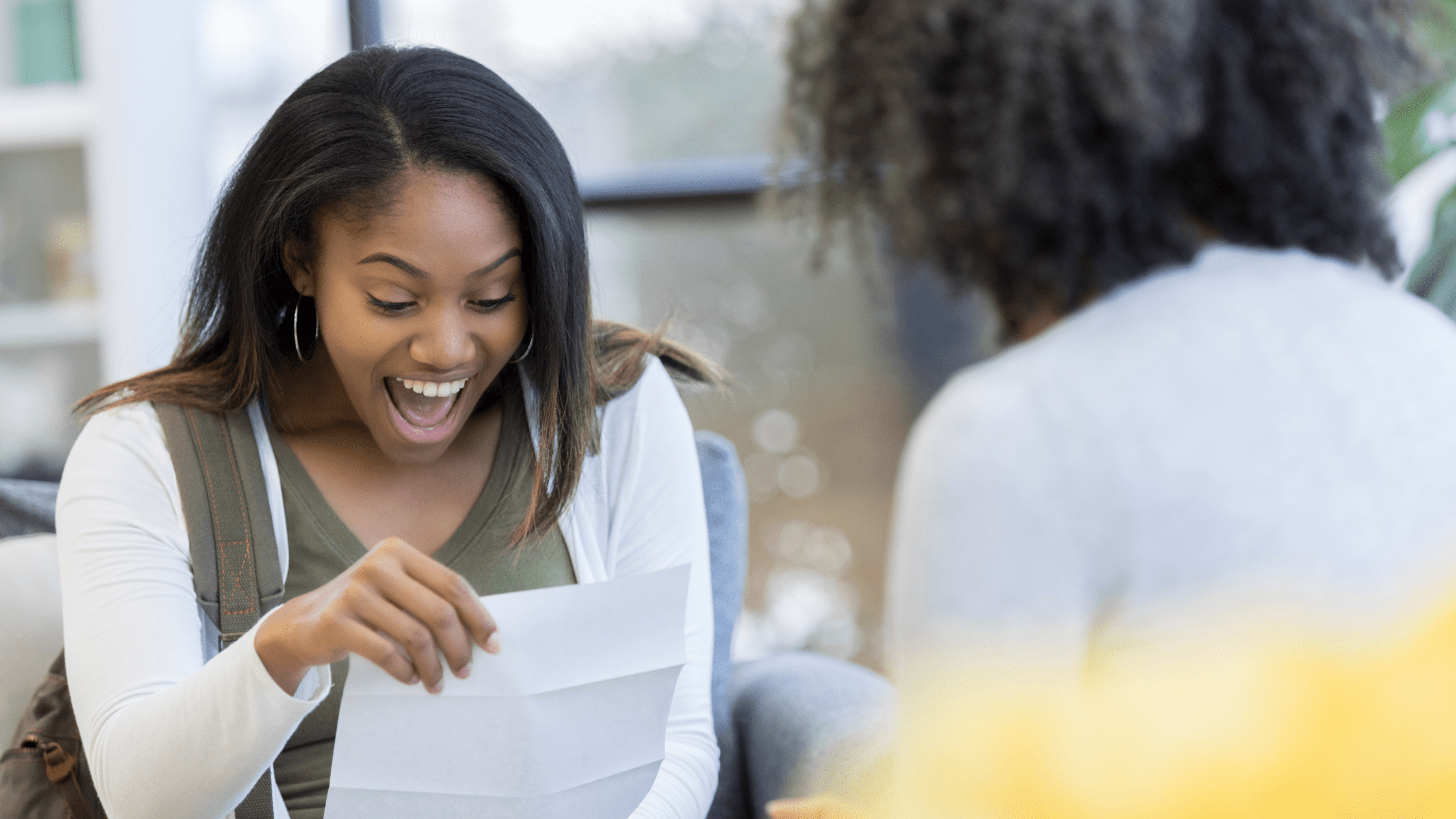 A medical school student looking excitedly at a piece of paper after finding out that she passed Step 1.
