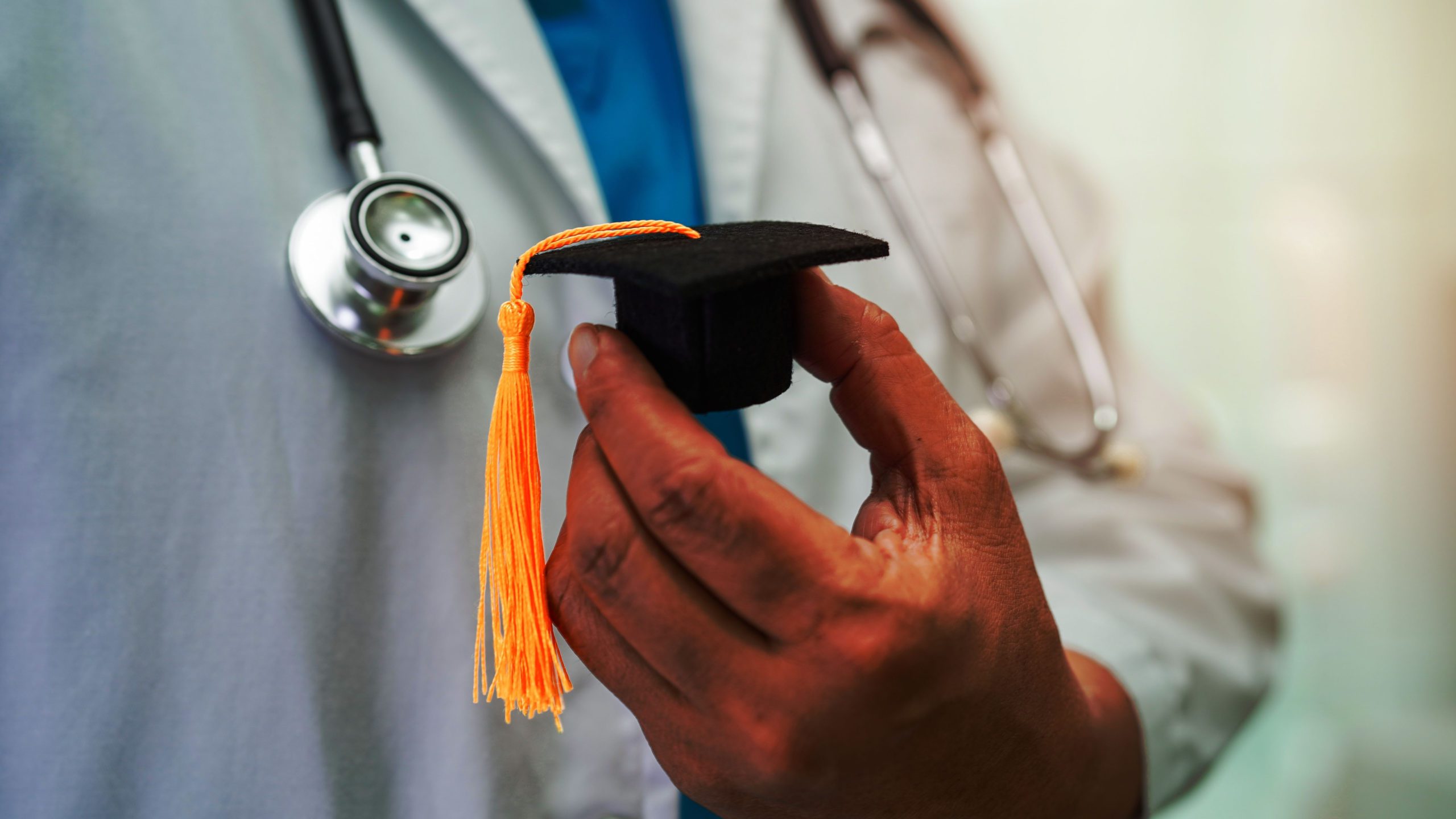 A doctor holding a small graduation cap after having completed the USMLE Step 3.