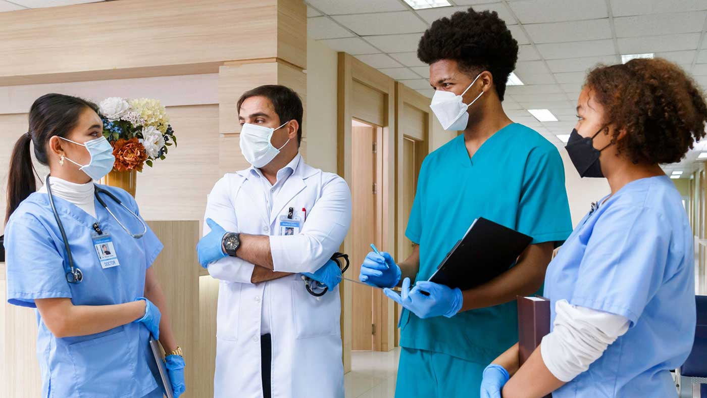 A group of medical school students on clinical rotations standing in a hospital wearing scrubs.