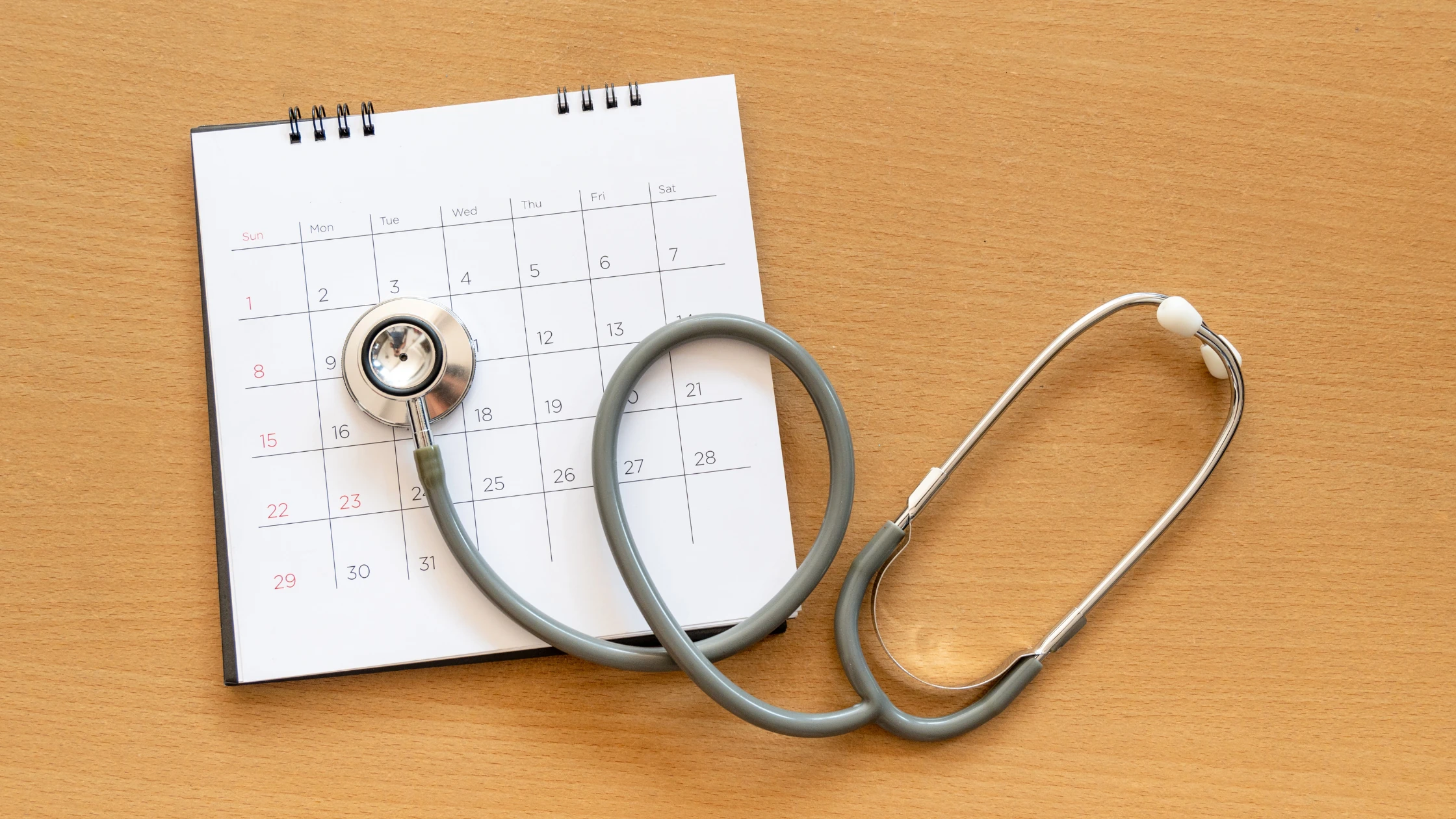 A calendar with a stethoscope sitting on top of it signifying the study routine of a medical school student.