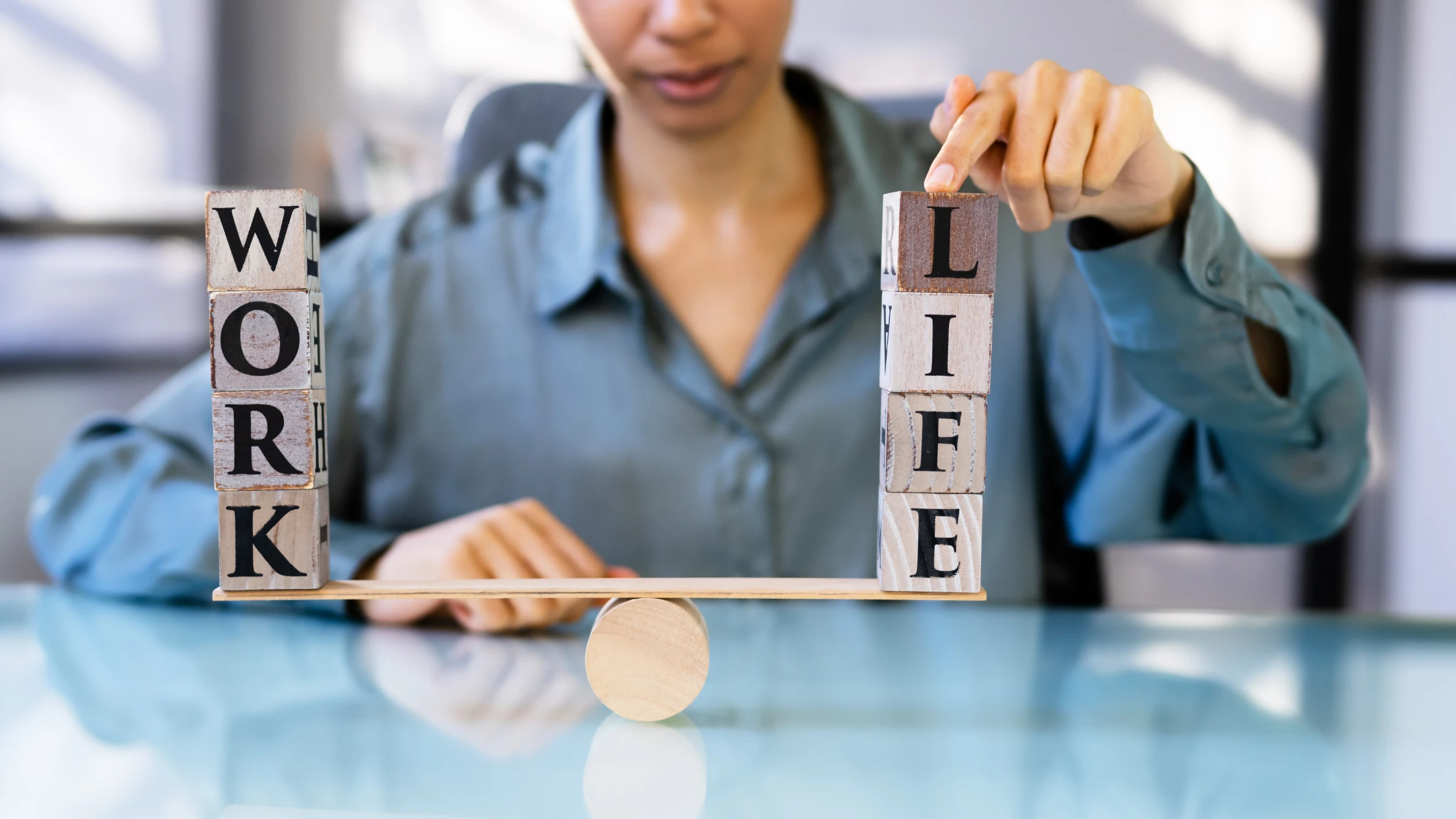Person balancing wooden blocks with the words 'WORK' and 'LIFE' on a seesaw, symbolizing work-life balance during USMLE prep.