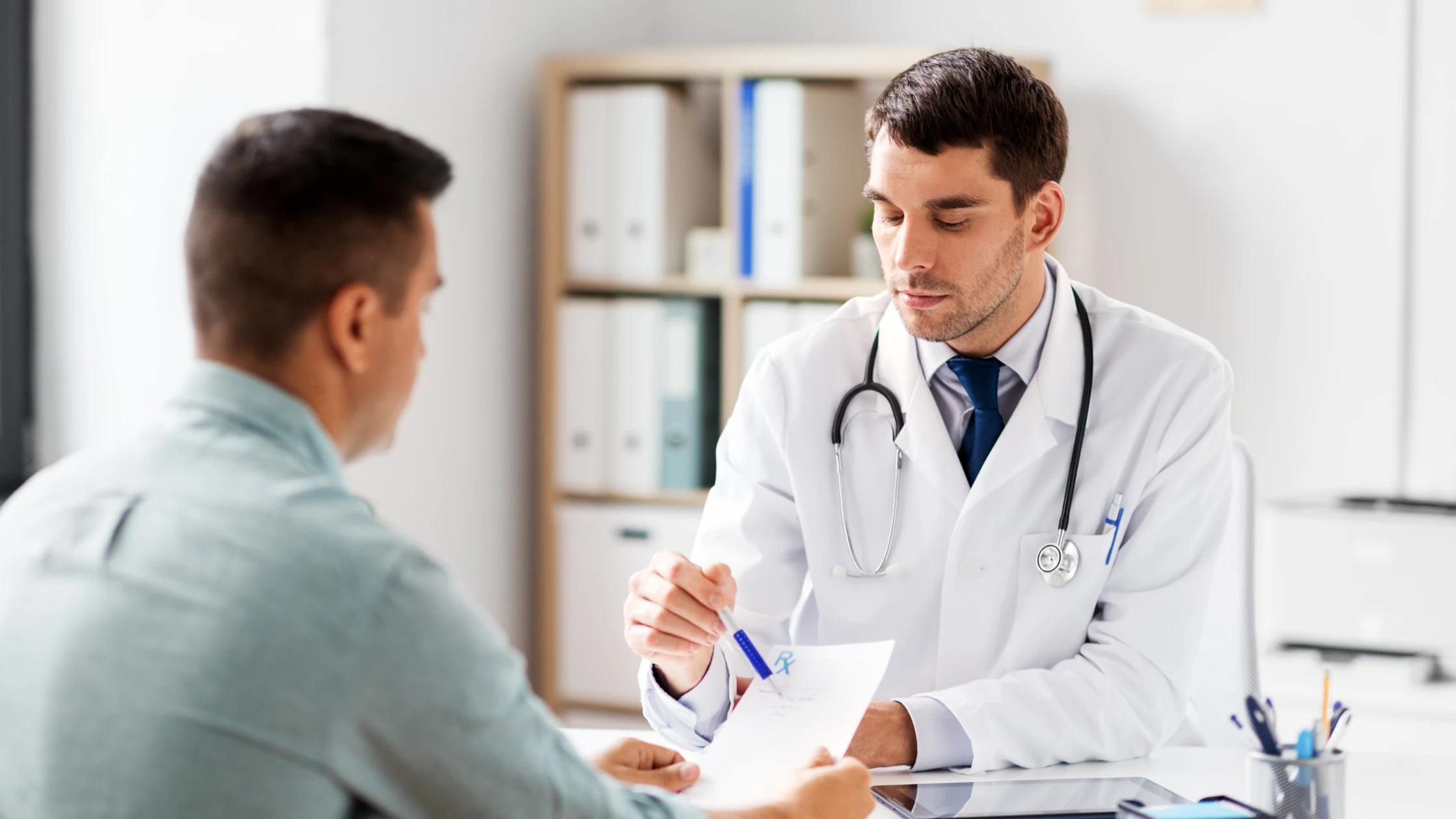A doctor in a clinical setting discussing a patient's medical history with the patient for the purpose of writing a SOAP note.
