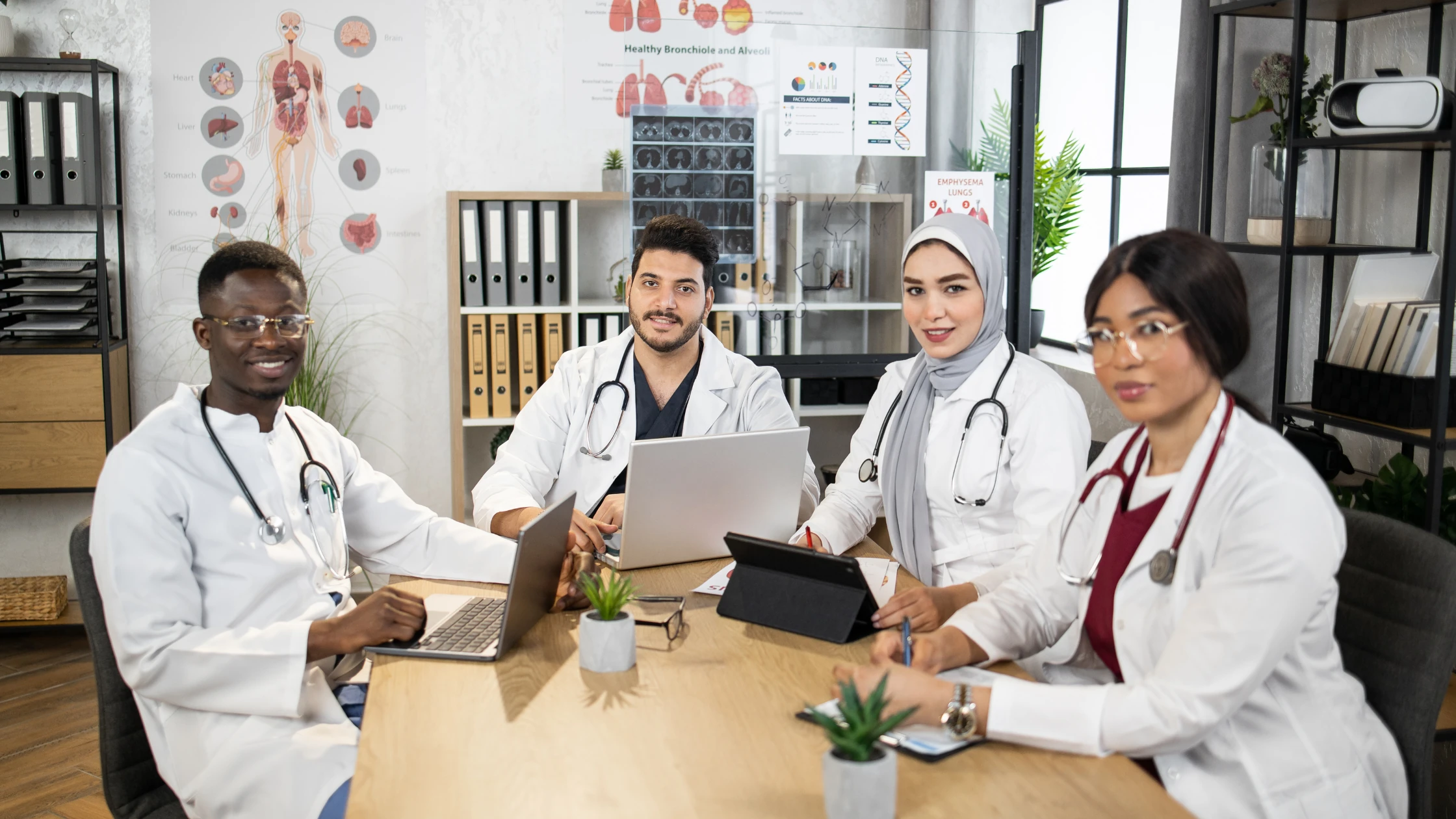 A group of diverse international medical graduates (IMGs) studying together at a table, using laptops and tablets, symbolizing collaboration and preparation for the USMLE Step 2 CK exam.