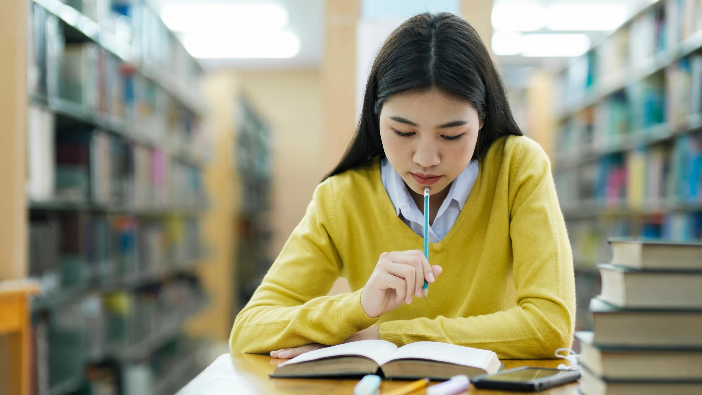 A medical student studies intently in a library, reviewing notes and resources, symbolizing the dedication and focused preparation needed to achieve a high score on the USMLE Step 2 CK.