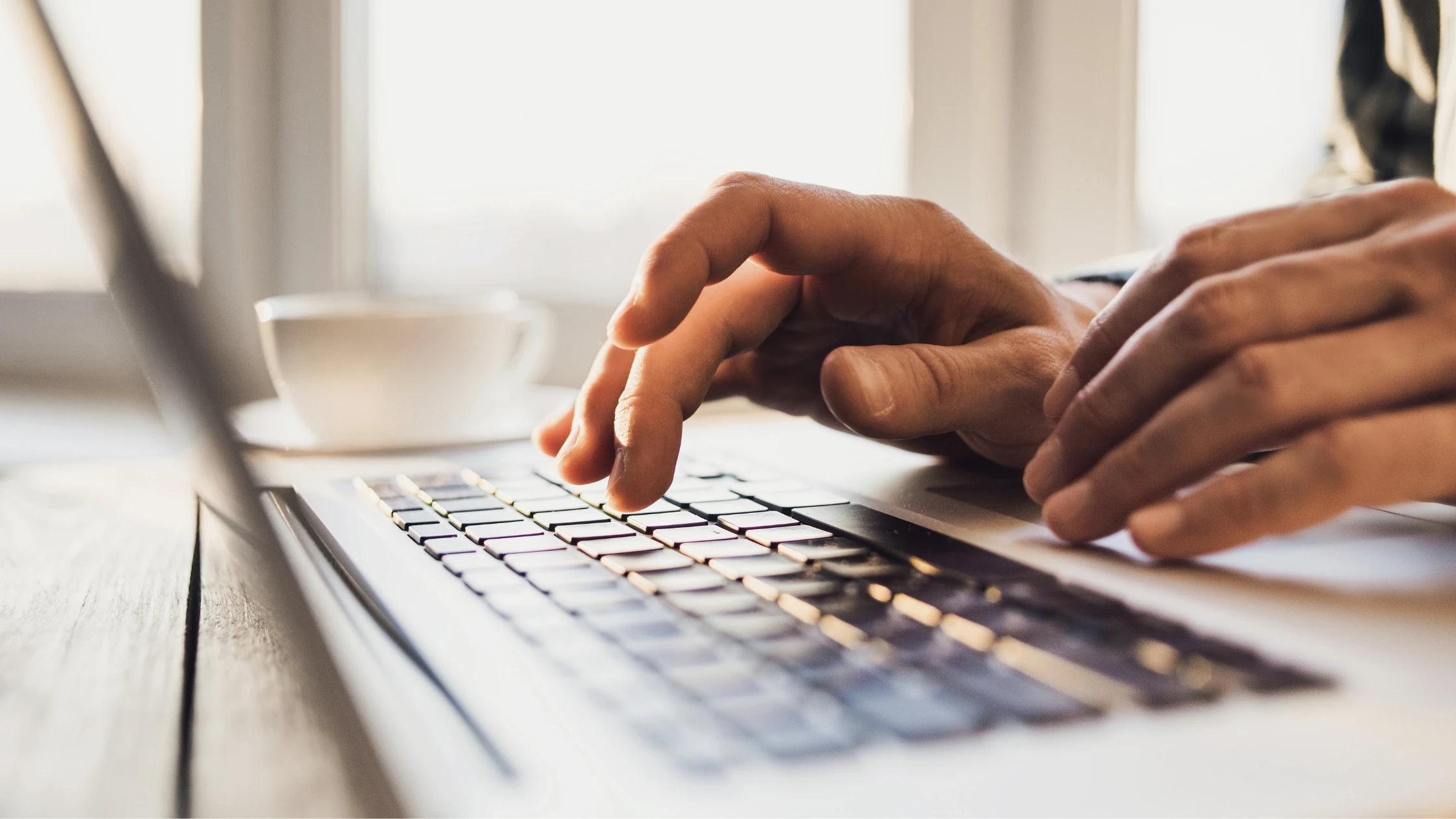 Close-up of hands typing on a laptop, submitting a USMLE test accommodations request online.