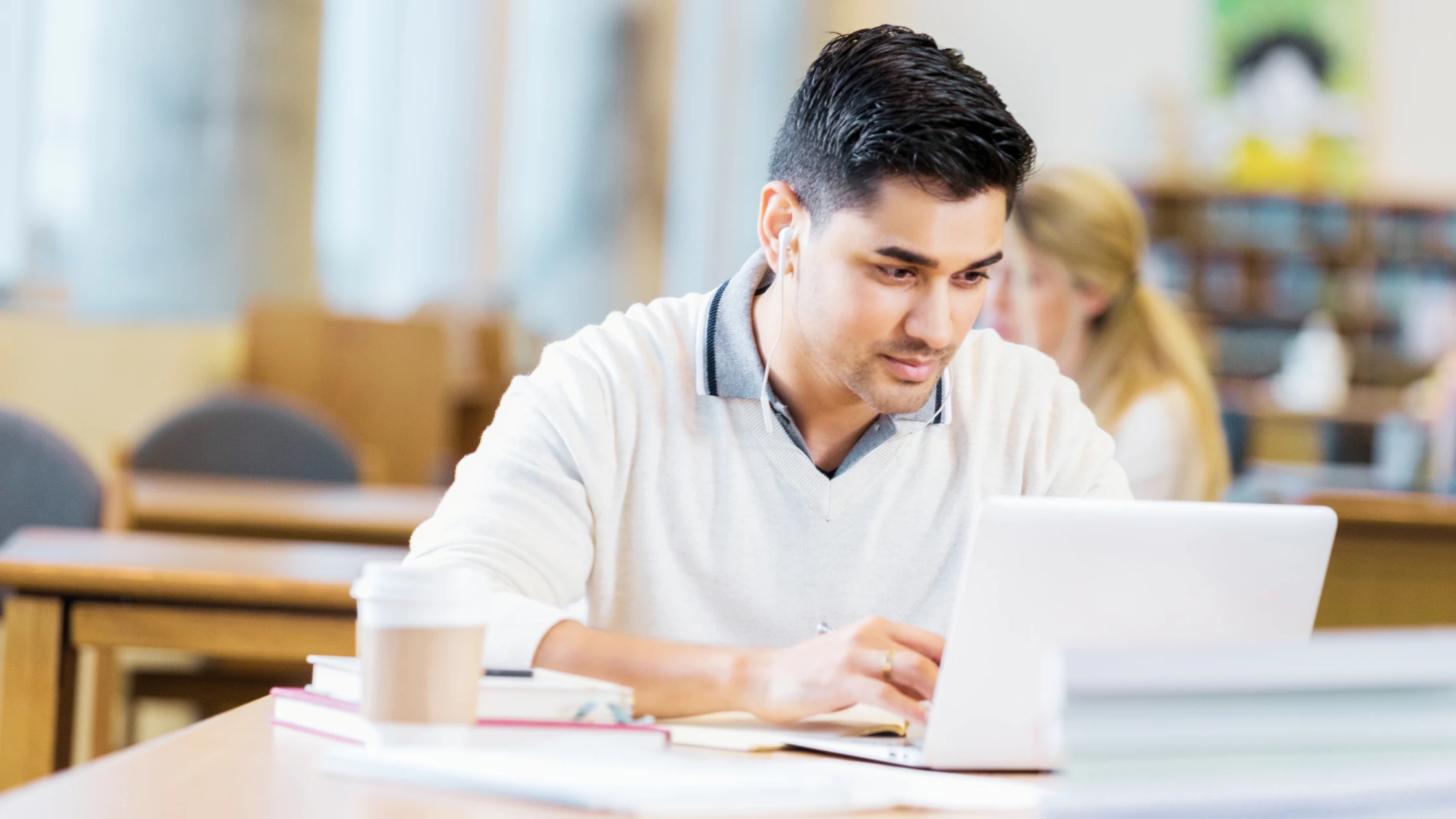 A medical student studying on a laptop, preparing for COMLEX and USMLE exams.