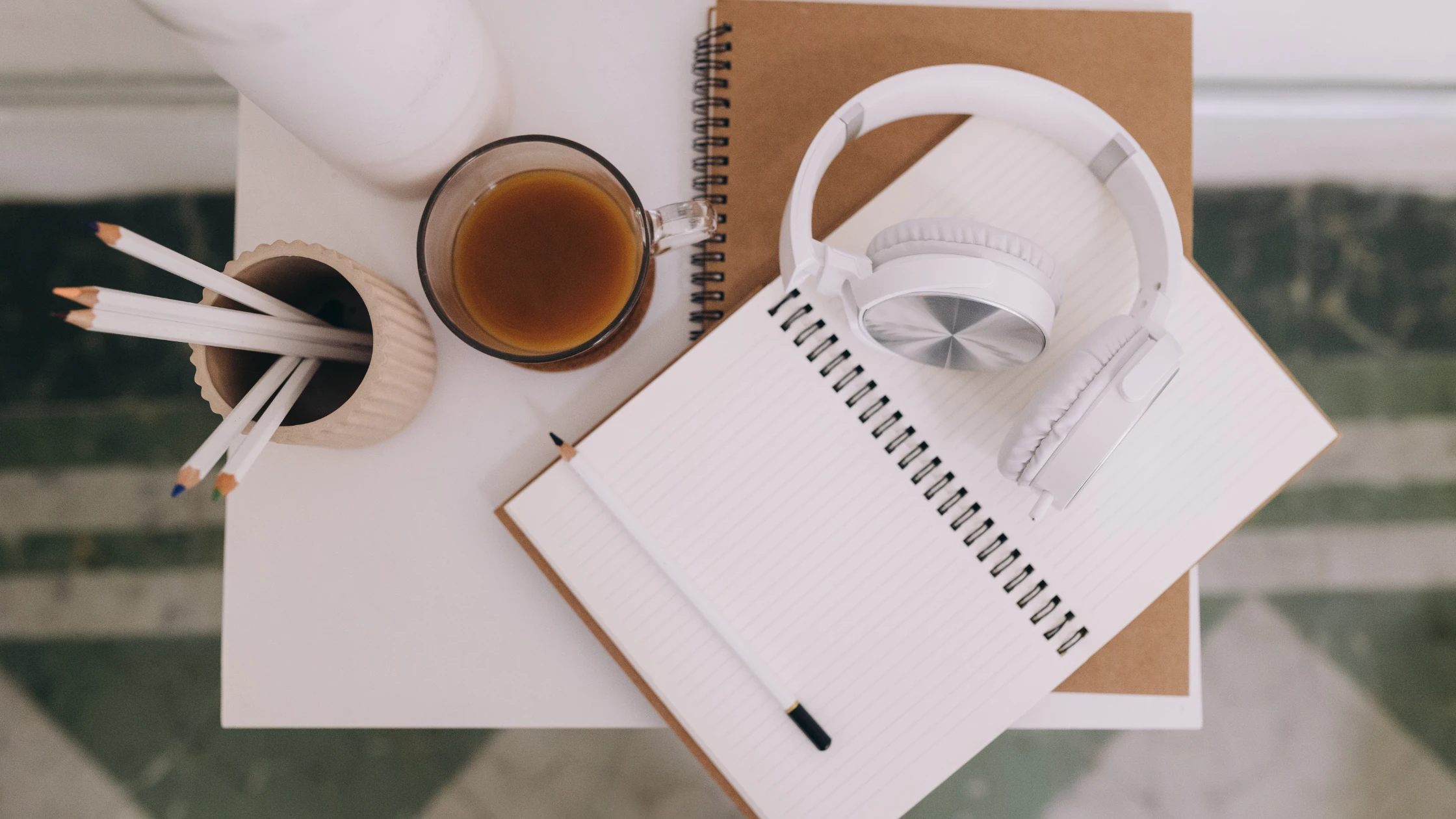 Study essentials for shelf exams including an open notebook, headphones, pencils, and a cup of coffee on a desk.