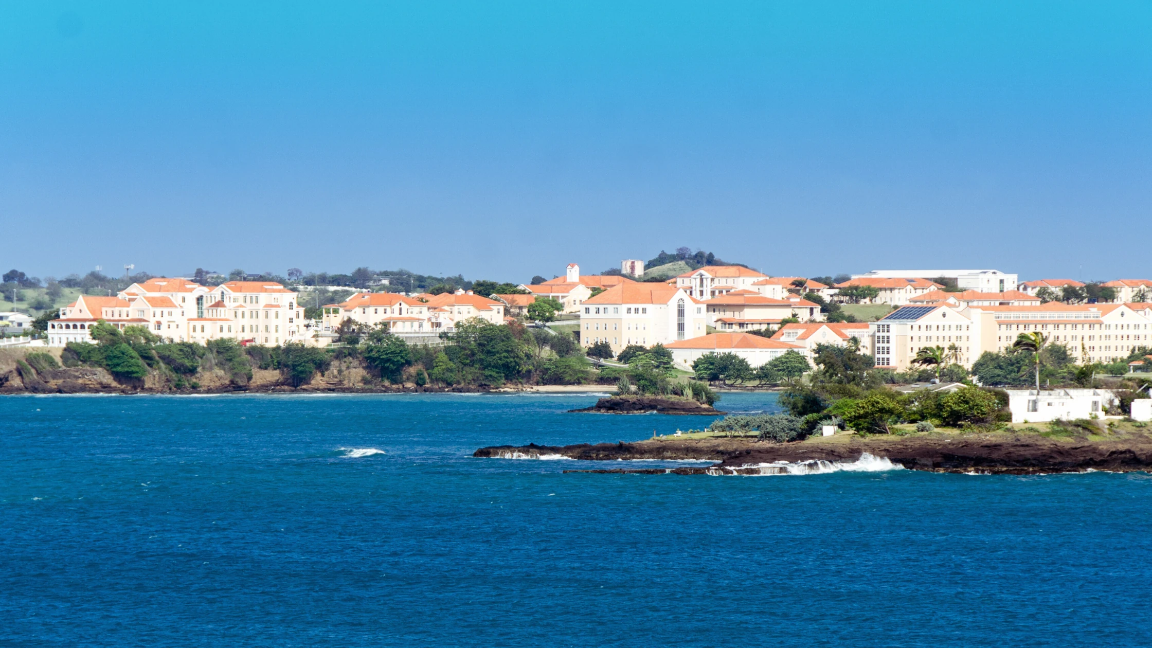 St. George's University campus in Grenada, with red-roofed buildings overlooking the Caribbean Sea.