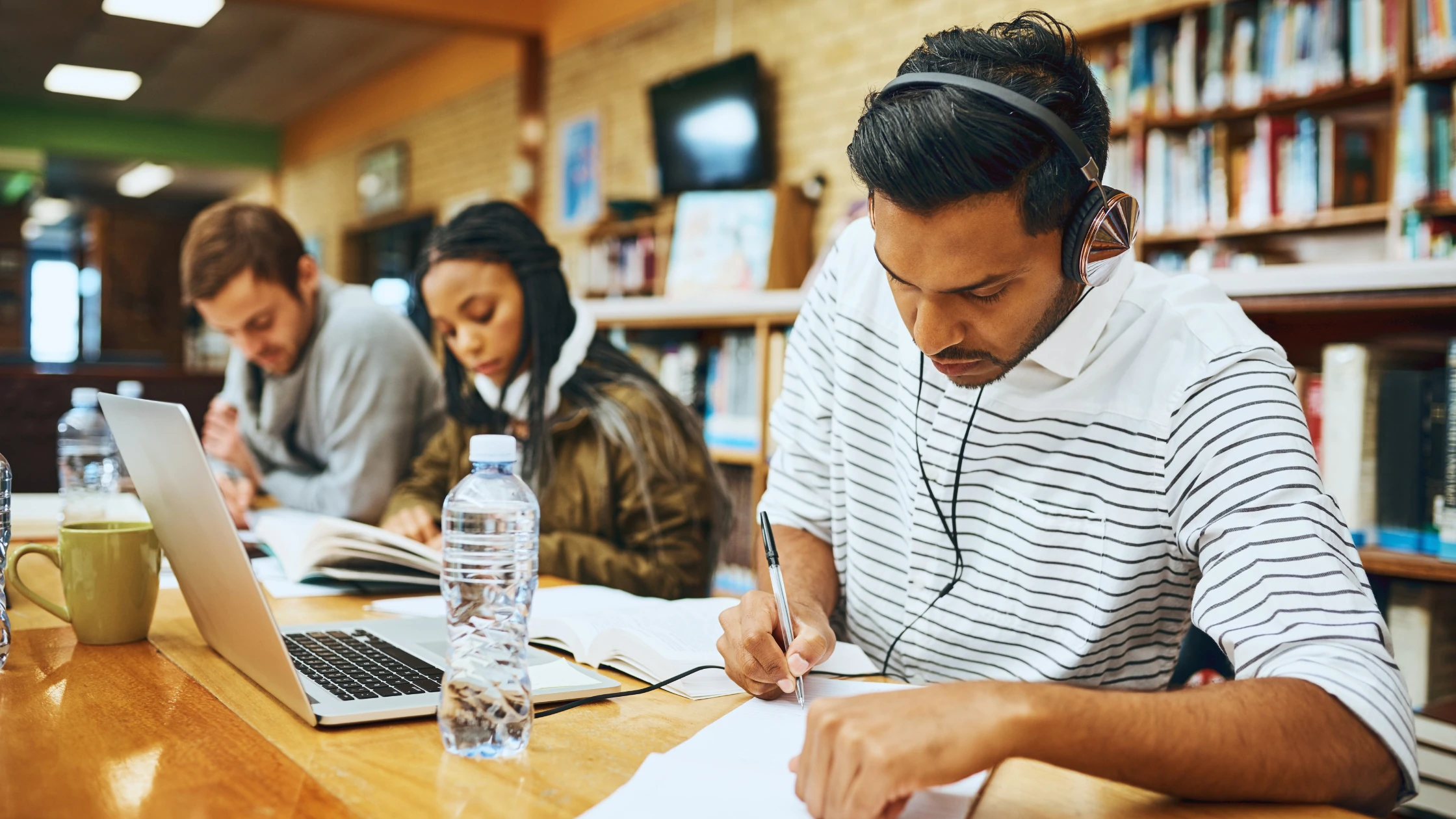 Medical students studying in a library, using notebooks, laptops, and headphones—illustrating focused microlearning techniques for USMLE Step 1 preparation.